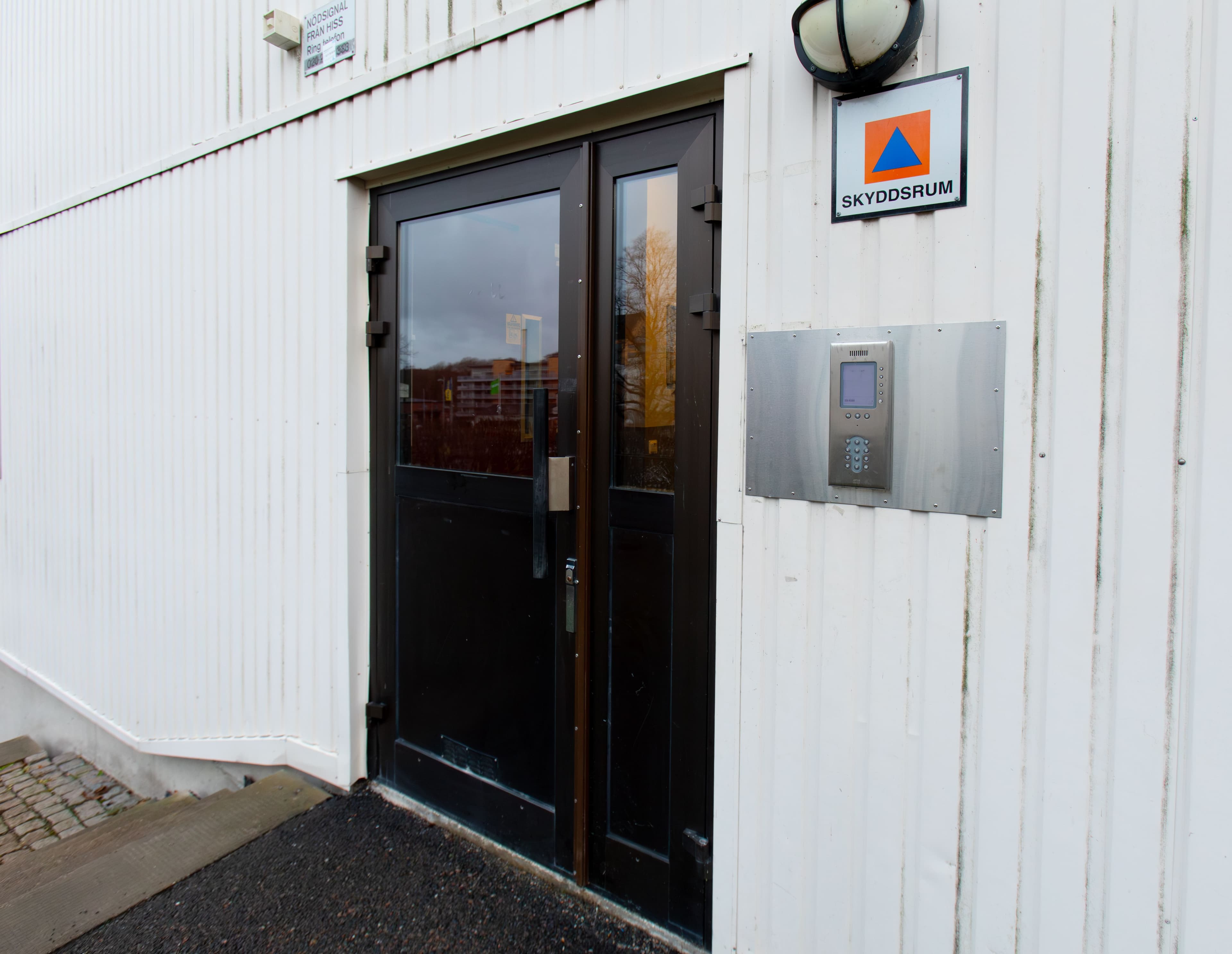 Ytterdörr till en byggnad med skyddsrumsskylt, som markerar var skyddsrummet är placerat i fastigheten.